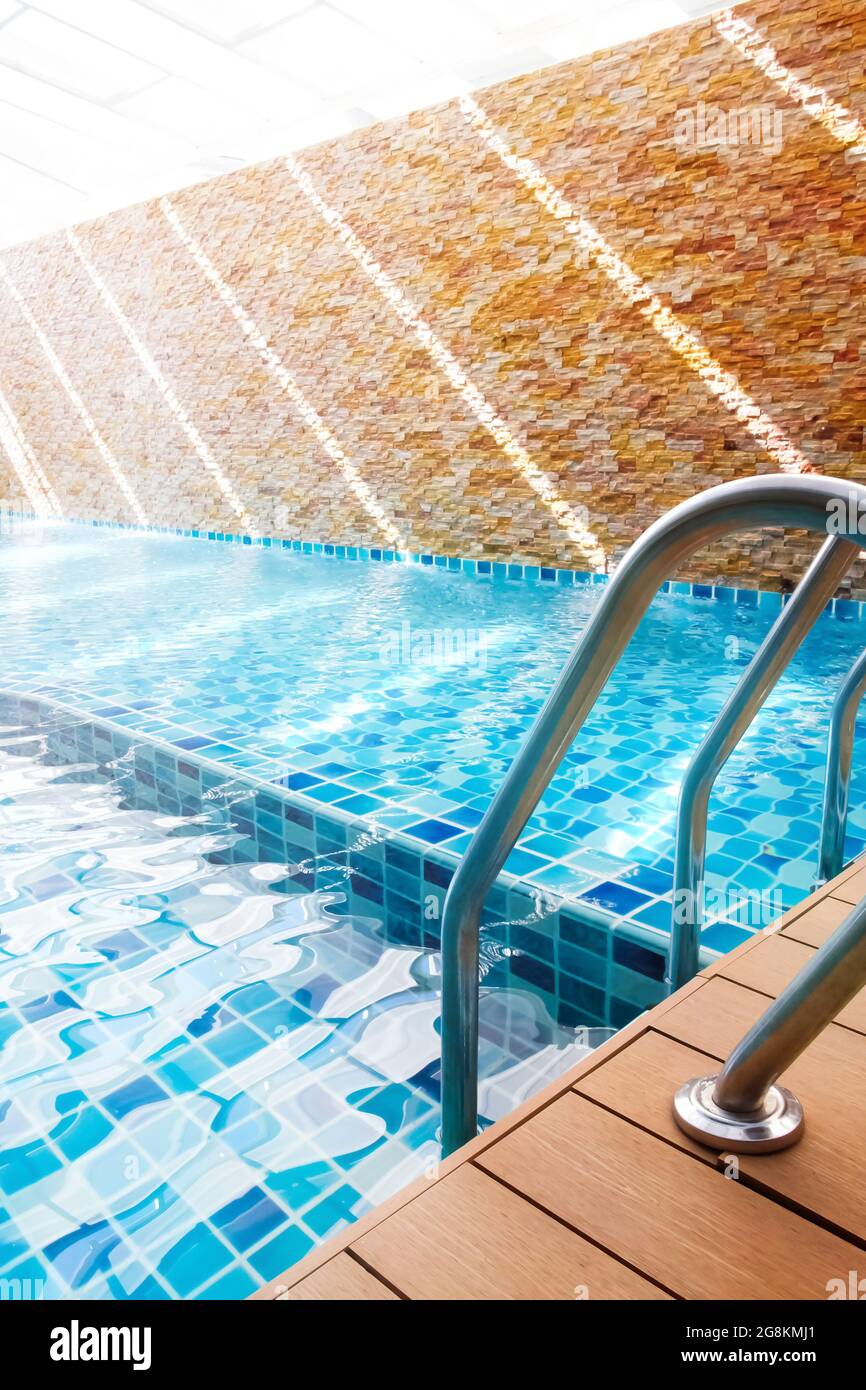 Une piscine turquoise vide avec poignées en échelle au lever du soleil. Mettre l'accent sur l'échelle des barres de maintien. Banque D'Images