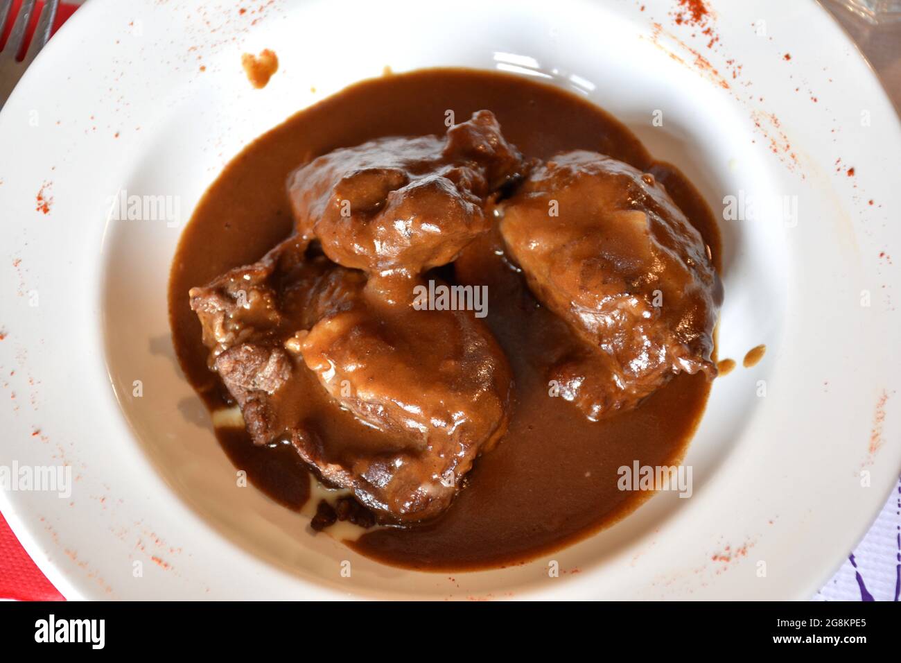 Assiette de joues de porc au vin rouge. Sauce au vin et compote de pommes comme base. Banque D'Images