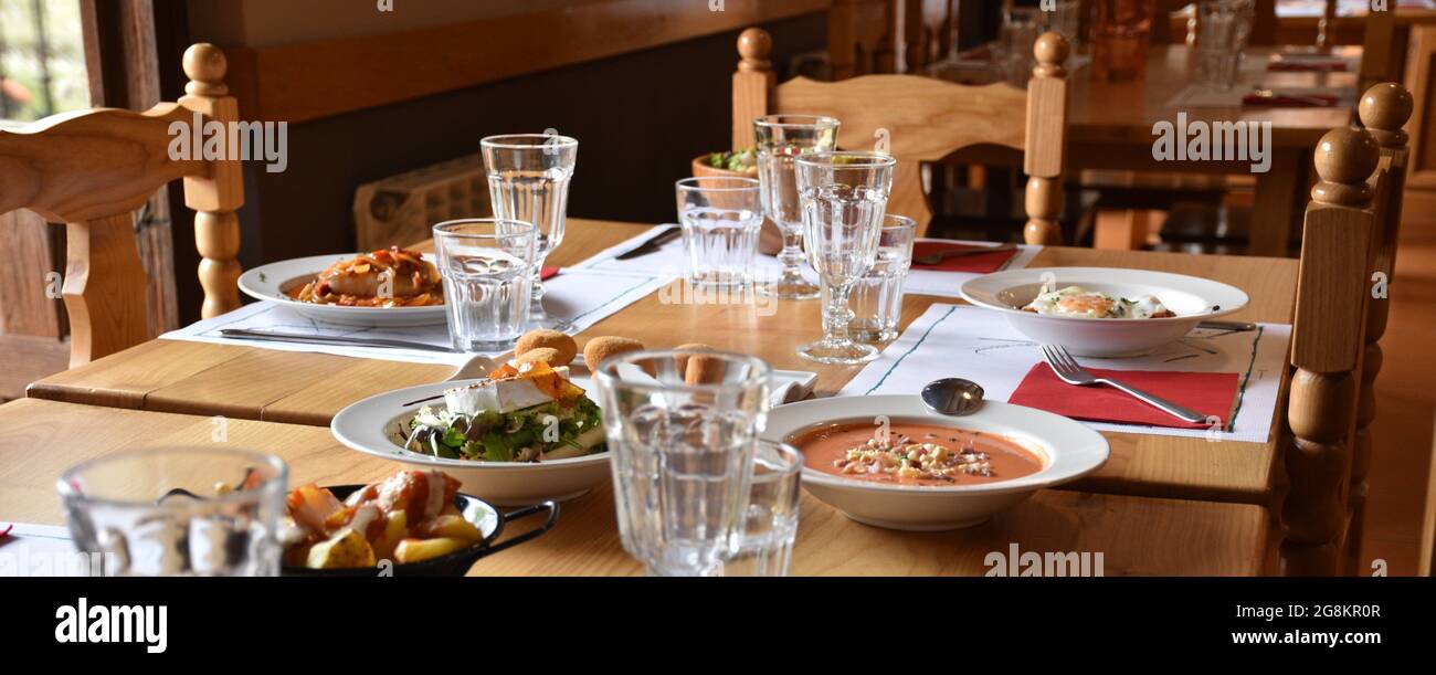 Restaurant avec différents plats et portions servis. Mobilier en bois, lumière naturelle, atmosphère agréable. Banque D'Images