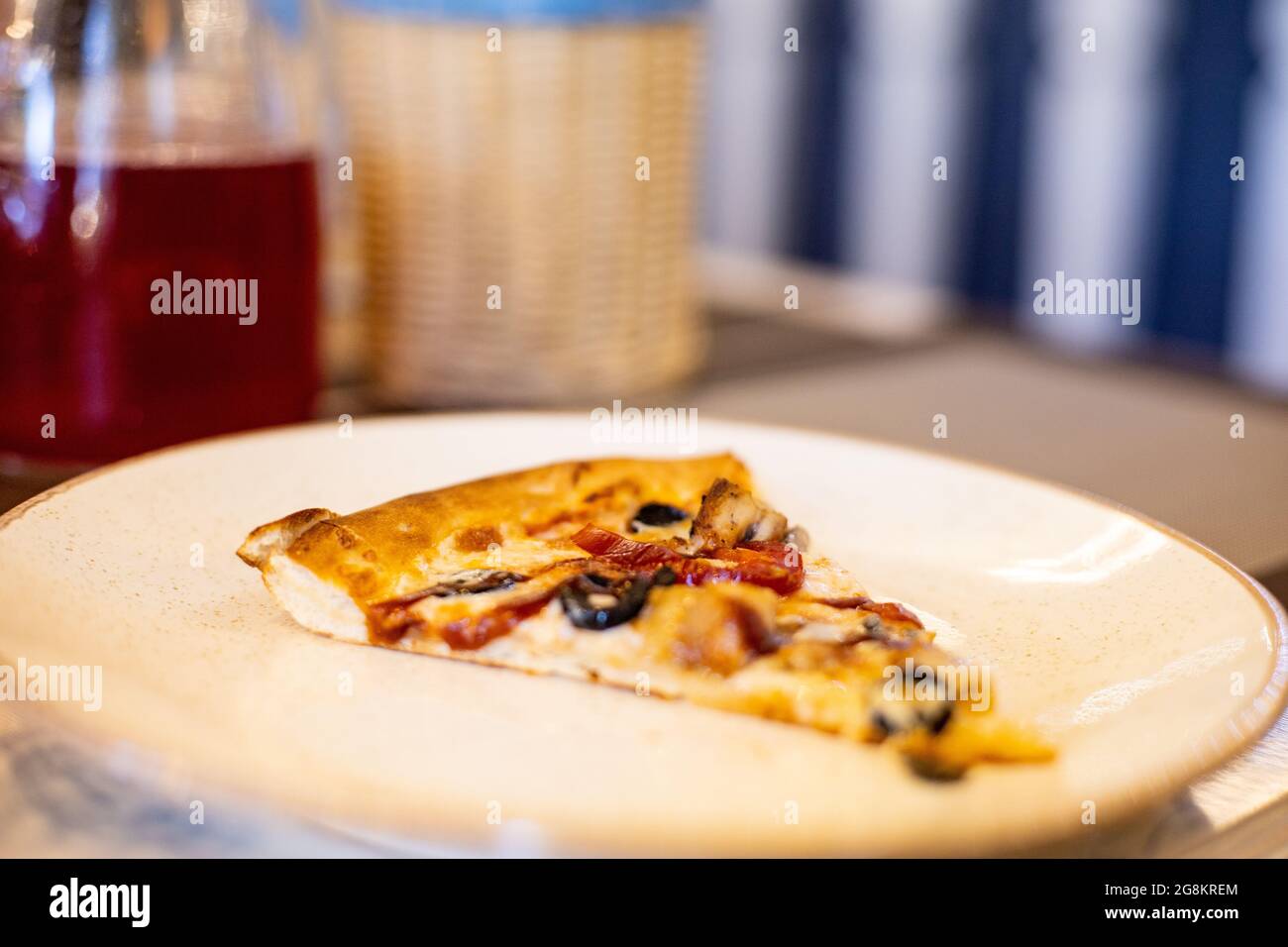 Une délicieuse tranche de pizza sur une assiette blanche sur la table du restaurant Banque D'Images