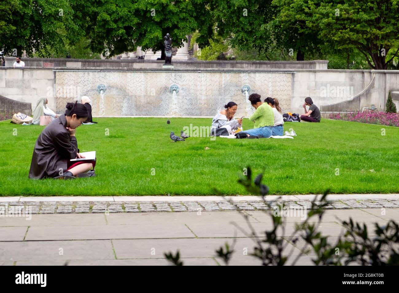 Les jeunes sont assis sur une pelouse dans les jardins du Festival de chantier naval de St Paul, lorsque les restrictions de la cavique sont assouplies au printemps 2021 City of London UK KATHY DEWITT Banque D'Images