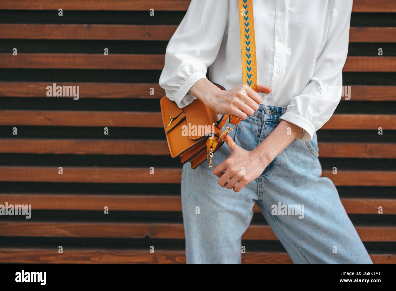 Photo de mode de la femme portant une chemise blanche, un Jean et un sac à  bandoulière marron sur fond de bois Photo Stock - Alamy