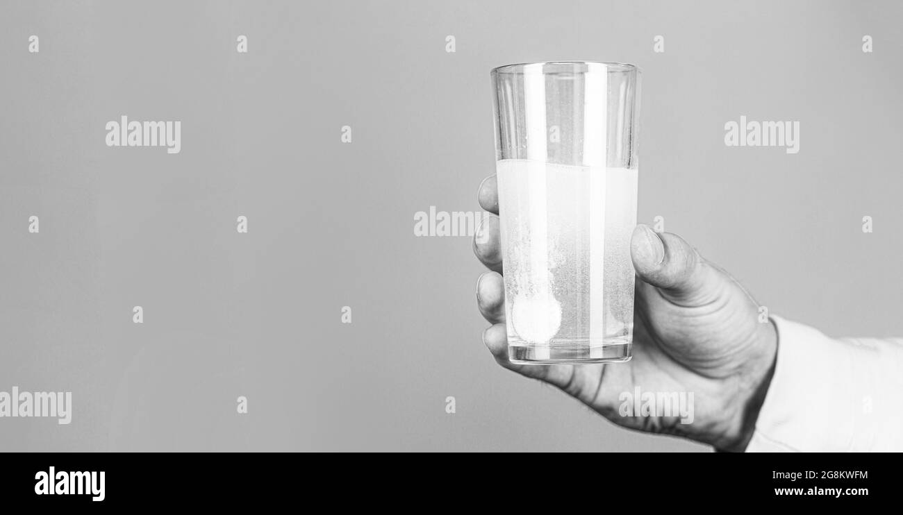 Verre de comprimé d'eau. Verre avec comprimé d'éperescence dans de l'eau avec des bulles. Gros plan de l'homme tenant une pilule. Noir et blanc Banque D'Images