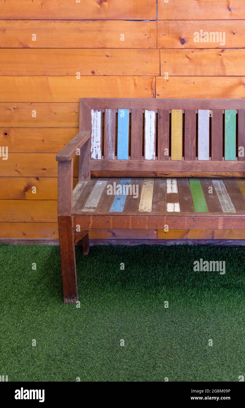 Le banc en bois peint avec la couleur pastel sur l'herbe artificielle devant le café, pour la détente du client sur la terrasse, devant Banque D'Images