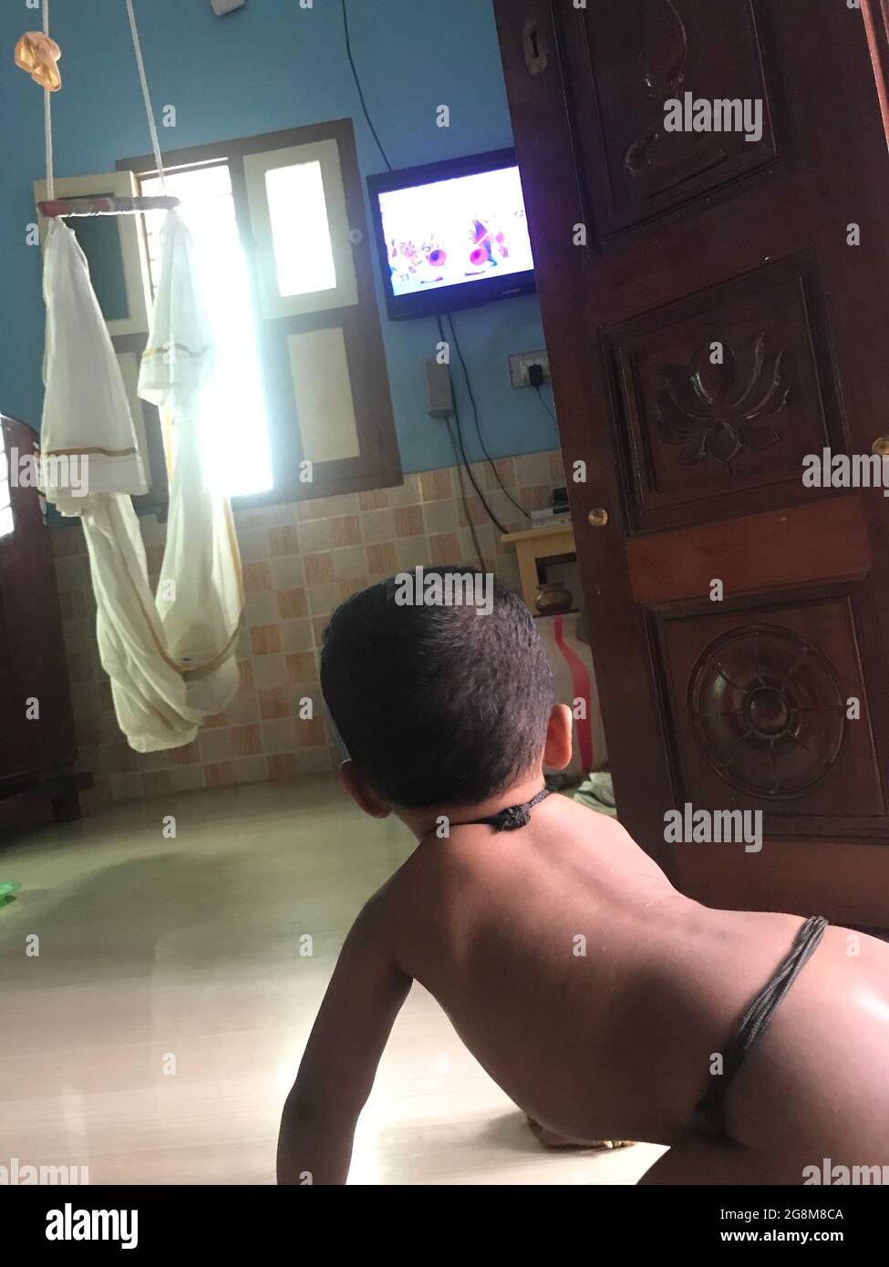 Bébé garçon enfant rampant et regardant la télévision pour regarder le dessin animé Banque D'Images