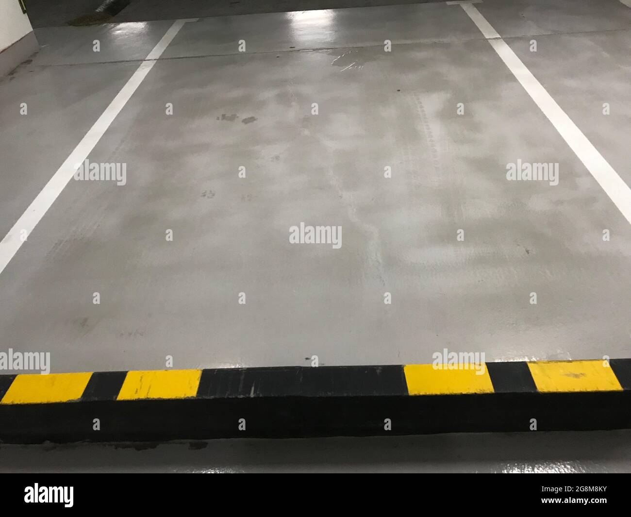 Parking au sous-sol une seule voie de stationnement séparée par deux lignes blanches et un butoir de voiture pour éviter d'entrer dans une autre voie de stationnement peinte par usi Banque D'Images