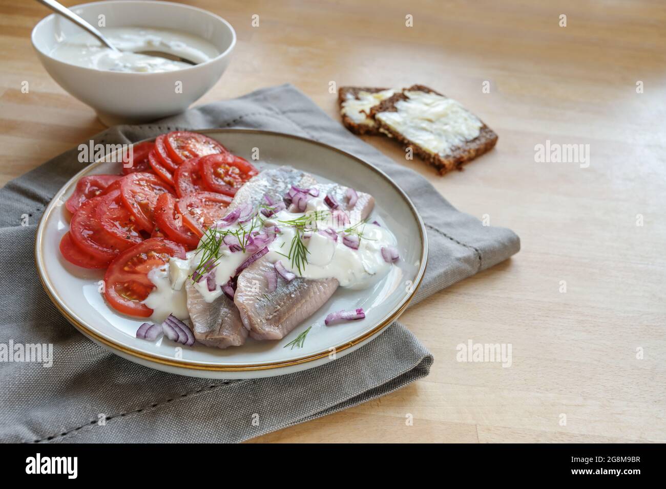 Filets de hareng salés traditionnels avec sauce à la crème, oignons rouges, garniture d'aneth et tomates sur une table en bois, espace de copie, concentration sélectionnée, profondeur étroite Banque D'Images