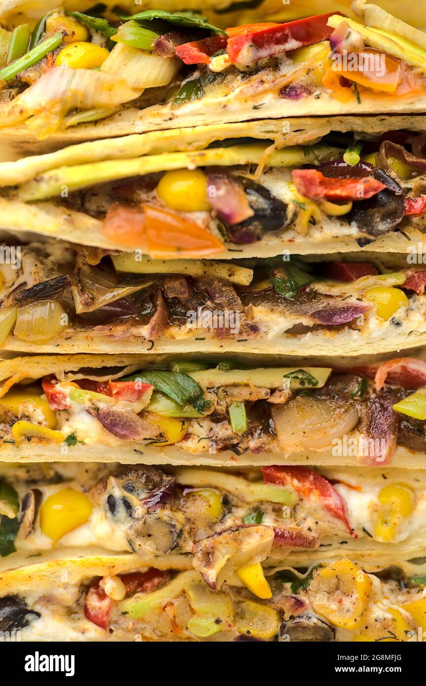 Belle vue détaillée de délicieux quesadillas mexicains crémeux aux haricots noirs avec du maïs doux, de l'avocat, de l'oignon rouge, du piment et de la coriandre Banque D'Images