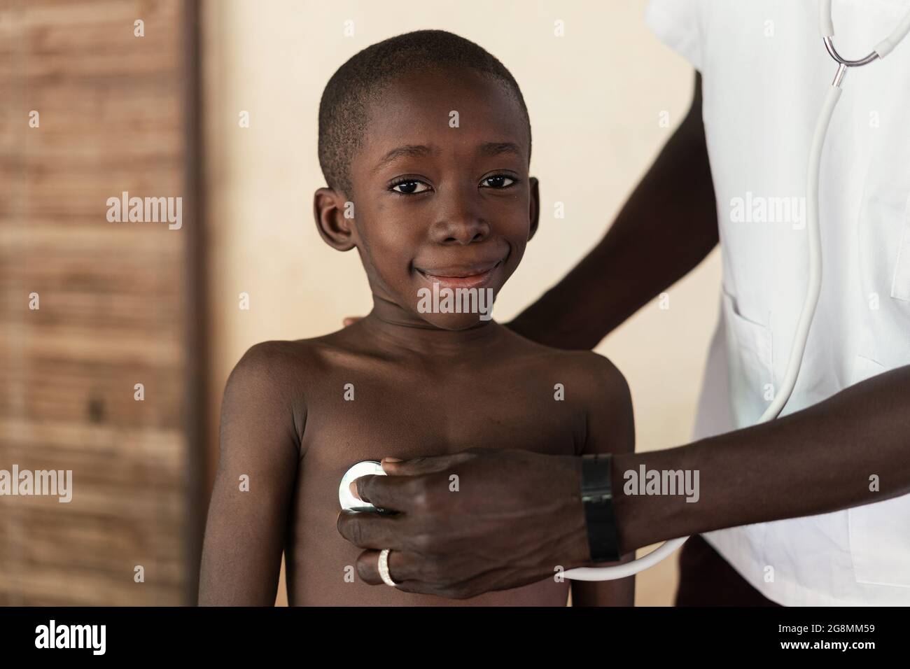 C'est l'image d'un médecin noir africain qui aide un petit garçon africain à sa place dans un village rural près de Bamako, Mali. Banque D'Images