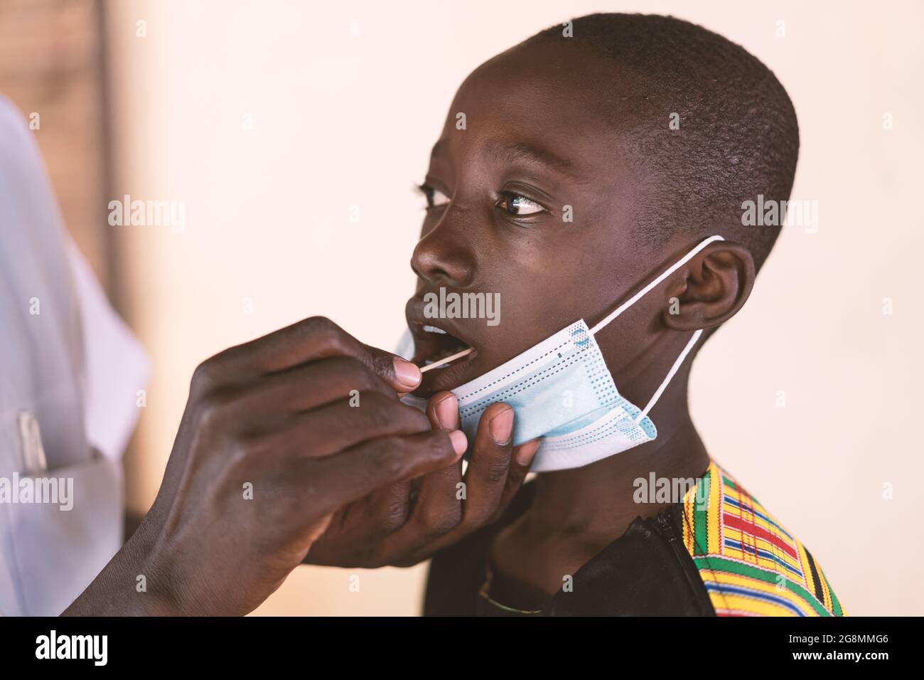 Un jeune garçon noir africain reçoit un coton-tige dans sa bouche pour tester la maladie du coronavirus à Bamako, au Mali. Banque D'Images