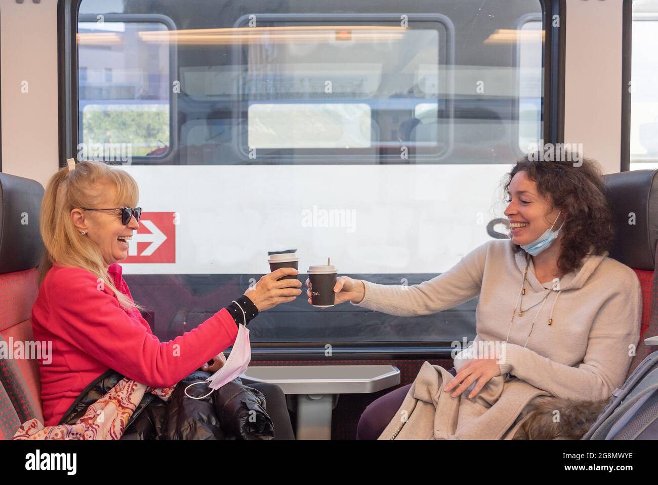 Des femmes heureuses voyageant en train souriant et prenant une tasse de café. Banque D'Images