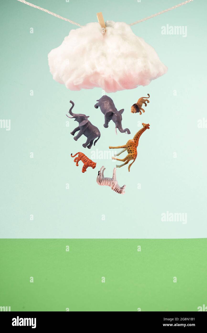 Enfant jouet animaux pleurant d'un nuage fixé sur une corde. Sur fond bleu pastel et vert tendance. Concept de protection de l'environnement abstrait minimal. Banque D'Images