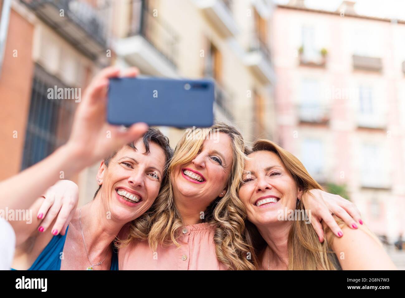Trois amies d'âge moyen qui se rassemblent pour prendre un selfie Banque D'Images