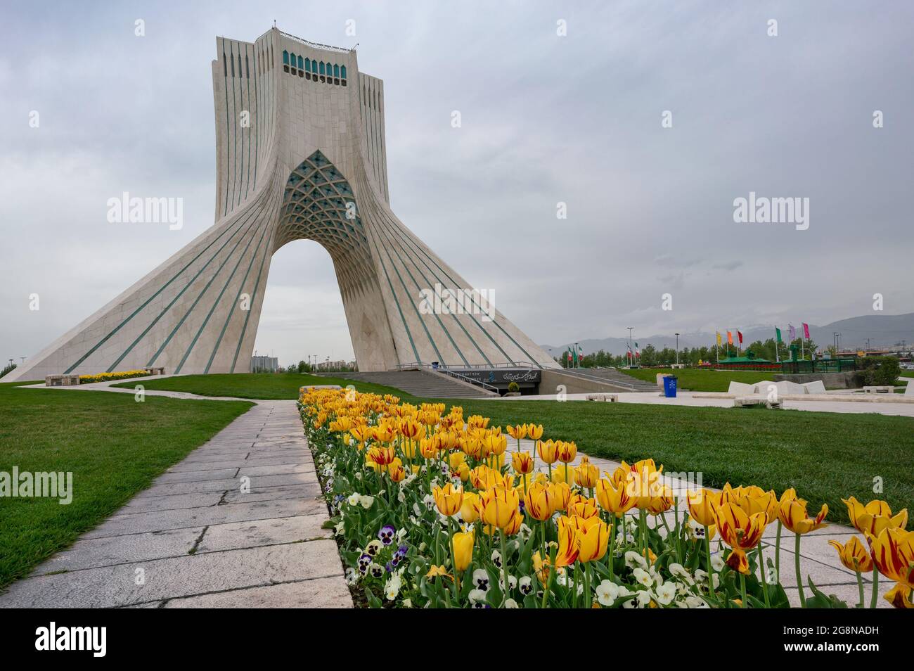 Téhéran, Iran - 04.10.2019: Tour Azadi complexe artistique et culturel à Téhéran, Iran. Tour de la liberté. Tulipes jaunes devant. Banque D'Images