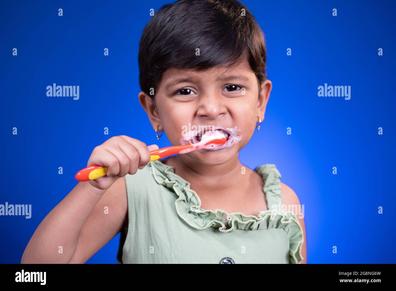 Portrait d'une fille qui se brossent les dents sur fond bleu - concept de l'enfant santé des dents par le nettoyage quotidien Banque D'Images