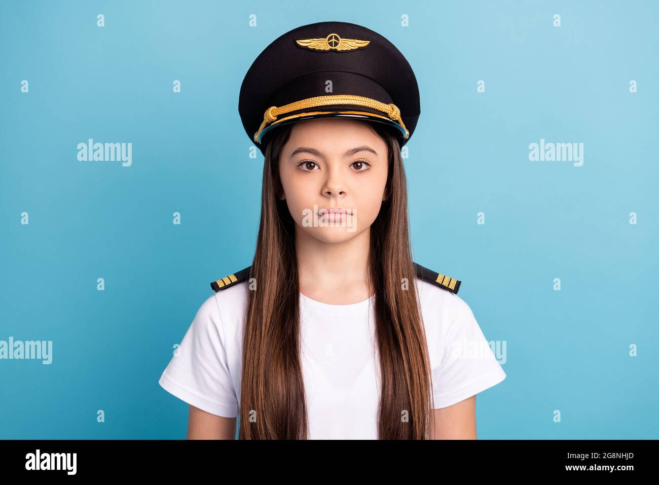 Photo de jeune fille sérieuse bonne apparence petite fille dans la casquette  pilote et t-shirt blanc avec de longs cheveux brunette isolés sur fond bleu  Photo Stock - Alamy