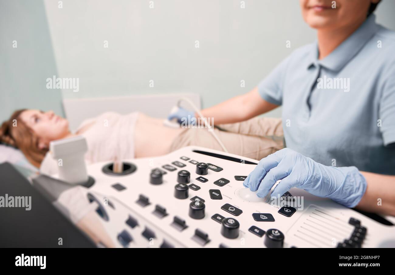 Se concentrer sur la main du médecin dans des gants stériles examinant une patiente avec une scanne à ultrasons. Échographiste effectuant une acquisition échographique. Concept de healt Banque D'Images