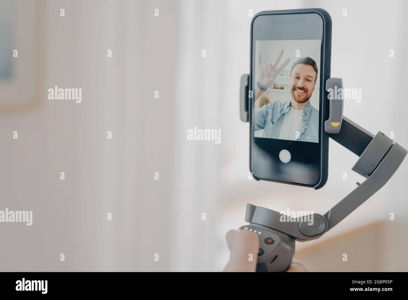 Main mâle tenant le stabilisateur de nacelle avec smartphone et souriant à la caméra Banque D'Images
