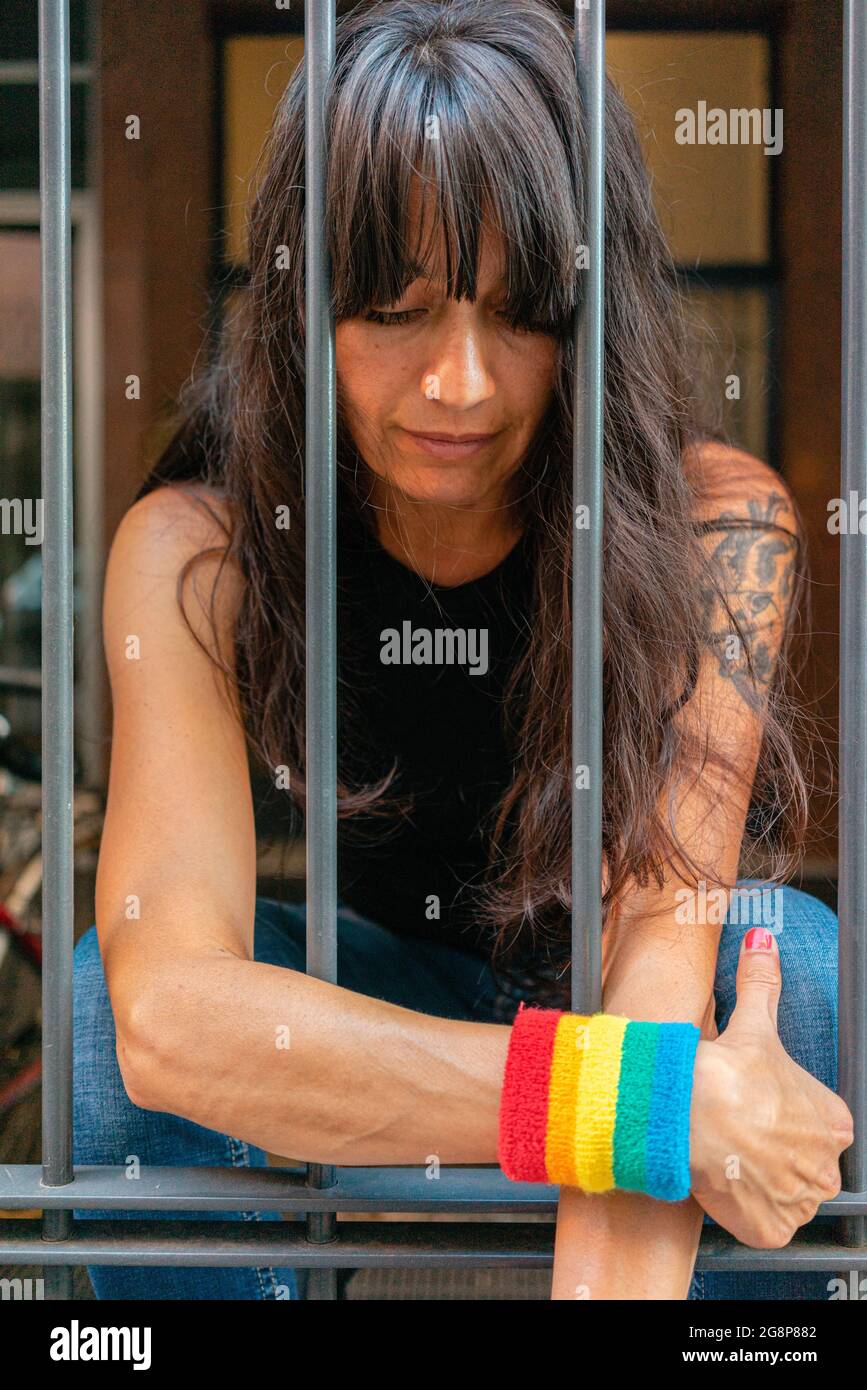 Petit foyer d'une femme italienne avec un bracelet LGBT derrière les barreaux Banque D'Images