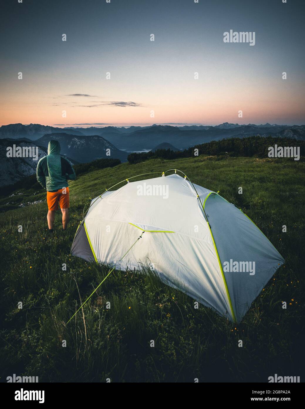 un homme devant une tente de camping se lève au lever du soleil le matin en  autriche Photo Stock - Alamy