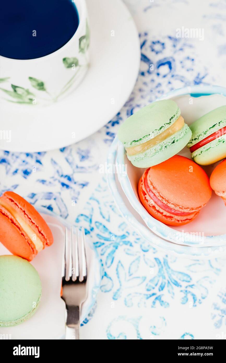 Thé aux papillons bleus et macarons ou macarons verts et orange Banque D'Images