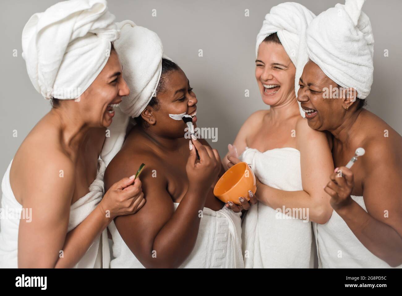 Les amies multiraciales rient pendant la procédure de soin de la peau Banque D'Images