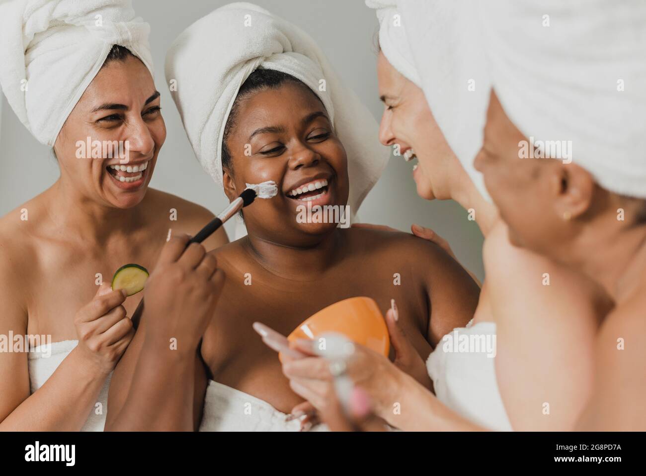 Femme noire appliquant le masque en argile près de amies heureuses Banque D'Images