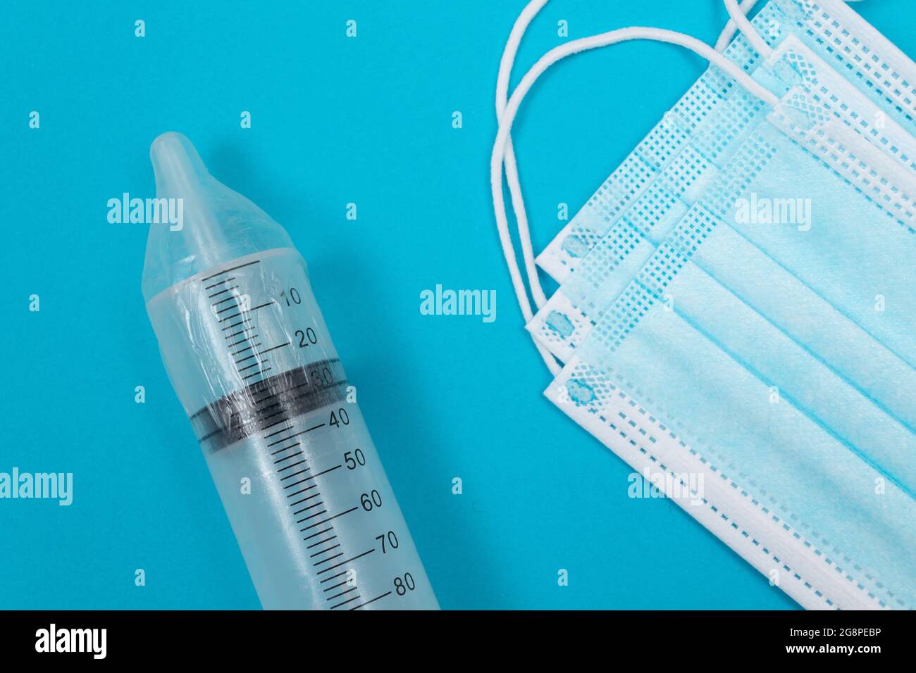 Vaccin sûr, anti-vaccin concept - seringue dans un condom se trouve sur la table bleue en clinique ou à l'hôpital. Méfiance à l'égard de la vaccination. Immunité naturelle. Scepticisme à propos du vaccin. Liberté et droits de l'homme Banque D'Images
