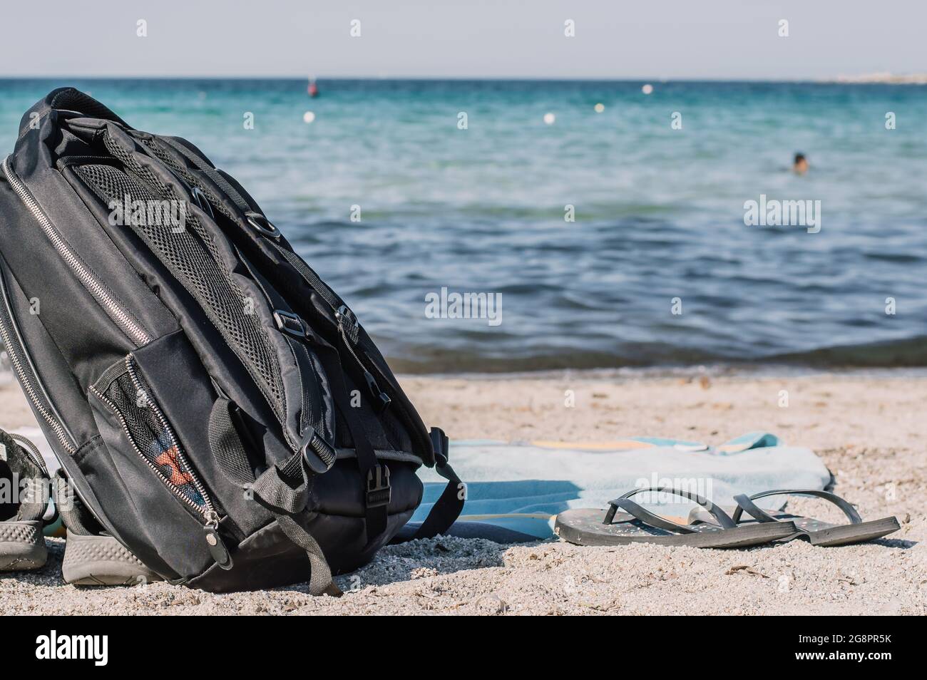 Un sac à dos noir élégant pour les voyageurs sur le rivage. Le concept de voyage, de vacances, de liberté. Paysage tropical vide avec une plage de sable au bord de la mer.COP Banque D'Images