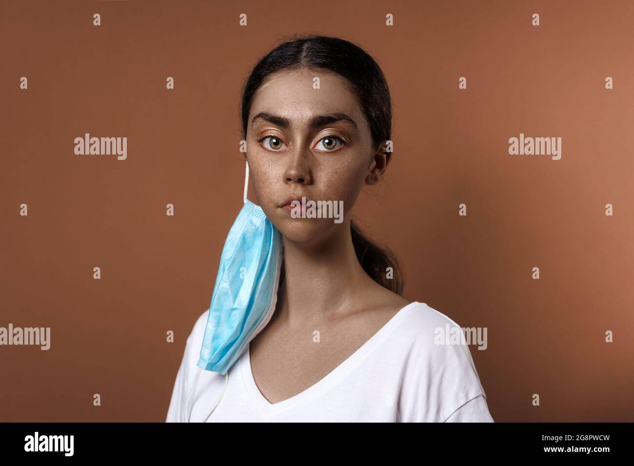Portrait d'une femme africaine aux traits hypertrophiés du visage, portant un masque. Arrière-plan marron. Un portrait irréel, comme un extraterrestre. Le concept de la vaccination Banque D'Images