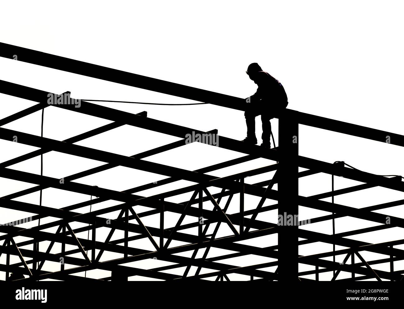 Un homme assis sur une poutre en treillis d'acier, des tuyaux chromés isolés sur le fond. Art design structure de construction métallique horizontale pour entrepôt de toit. Abstr Banque D'Images