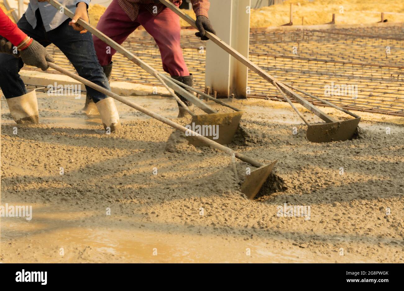 Trois ouvriers de la construction nivelant la chaussée en béton. Banque D'Images