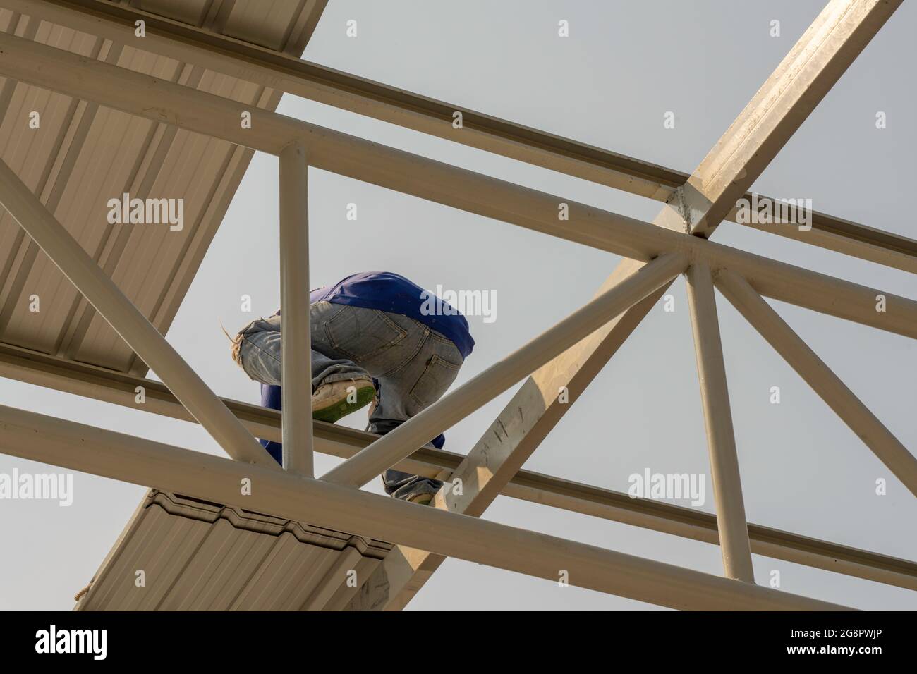 Ouvrier installant la tôle de couverture sur la construction de treillis et de cadre en acier léger. Banque D'Images