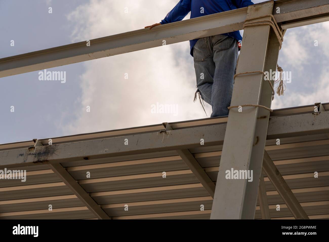 Un homme debout sur la tôle de toiture sur la construction de treillis et de cadre en acier léger. Banque D'Images