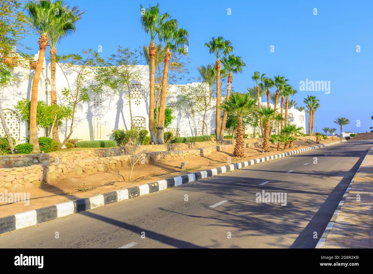 La vue sur la route et les palmiers près des bâtiments du territoire des hôtels en Egypte Banque D'Images