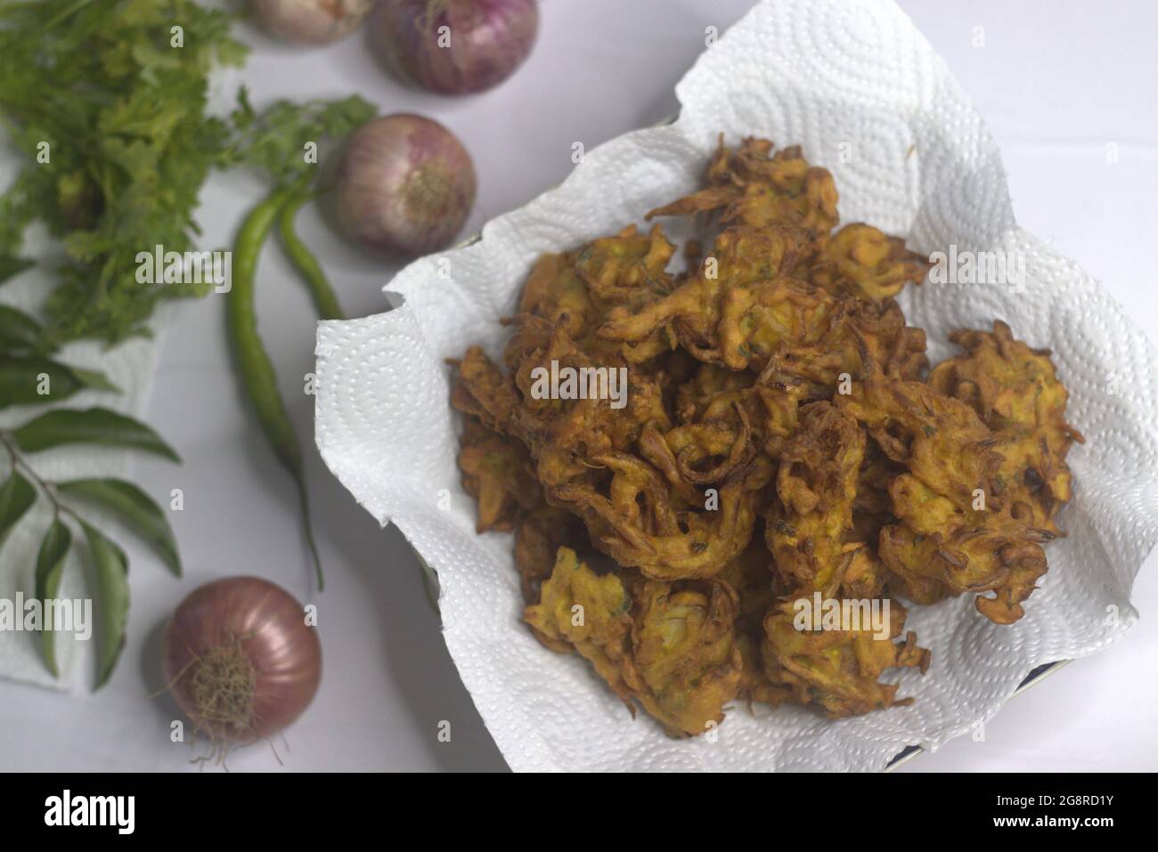 Beignets d'oignons. Tranches d'oignons frits enrobées de farine hachée et de masala. Une collation populaire en Inde communément connue sous le nom de pakoda d'oignon. Prise de vue sur b blanc Banque D'Images