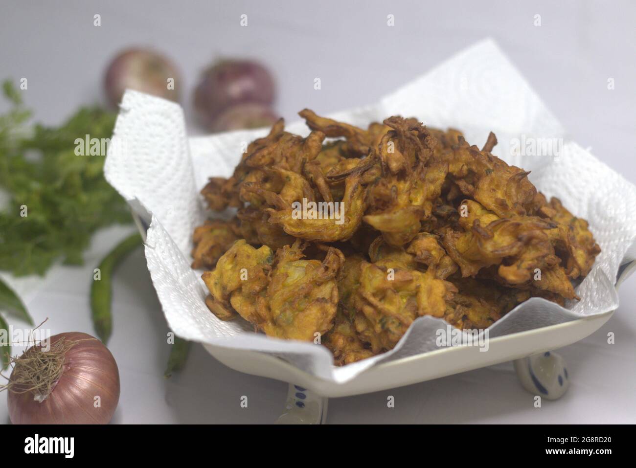 Beignets d'oignons. Tranches d'oignons frits enrobées de farine hachée et de masala. Une collation populaire en Inde communément connue sous le nom de pakoda d'oignon. Prise de vue sur b blanc Banque D'Images
