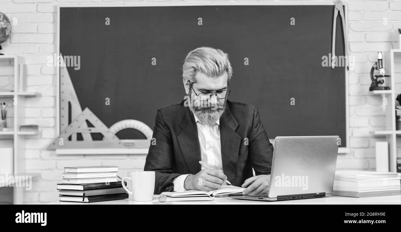 Technologie numérique. Enseignant en classe. Regardez la vidéo pour un didacticiel étape par étape. Le beau homme utilise la technologie moderne. Professeur d'école avec ordinateur portable. Web Banque D'Images