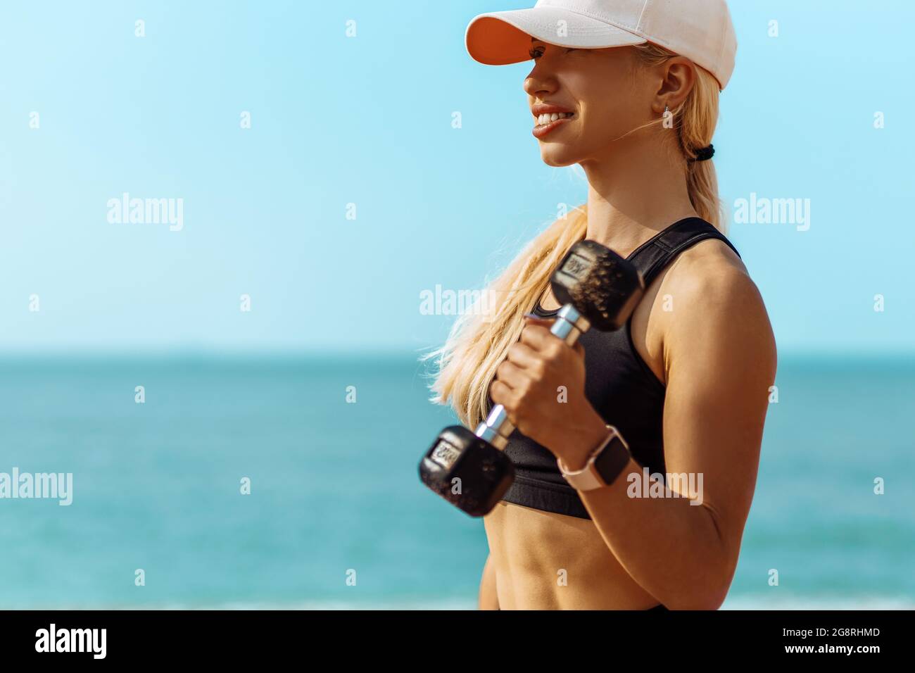 Pleine longueur, bonne santé jeune femme de forme physique, dans les vêtements de sport, faisant des exercices avec des haltères sur la plage, sportive belle jeune femme avec des haltères ou Banque D'Images