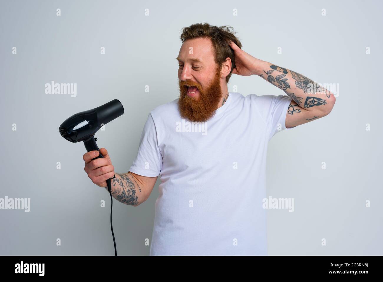 Homme heureux avec la barbe utiliser le sèche-cheveux comme microphone et  danse Photo Stock - Alamy