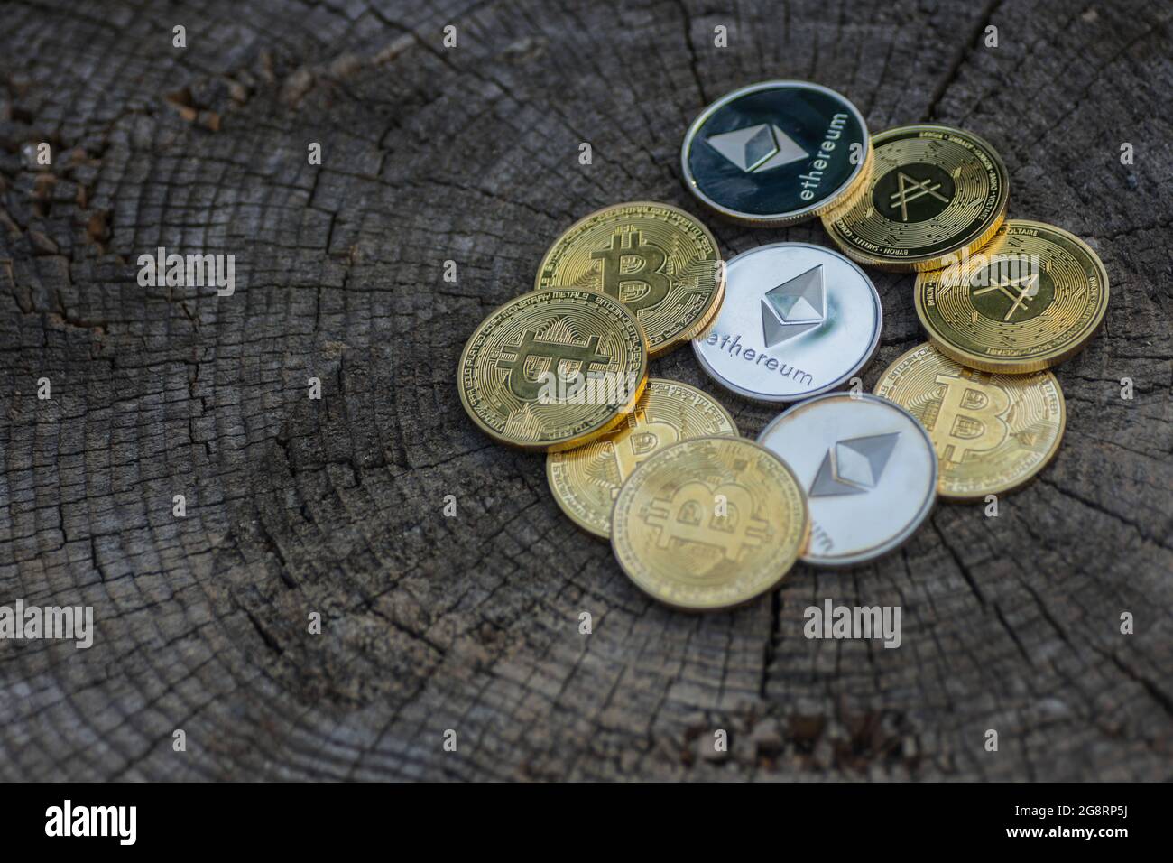 beaucoup de pièces d'or et d'argent valant l'éther bitcoin et ada de crypto-monnaie se trouvant sur un tronc d'arbre fissuré foncé Banque D'Images