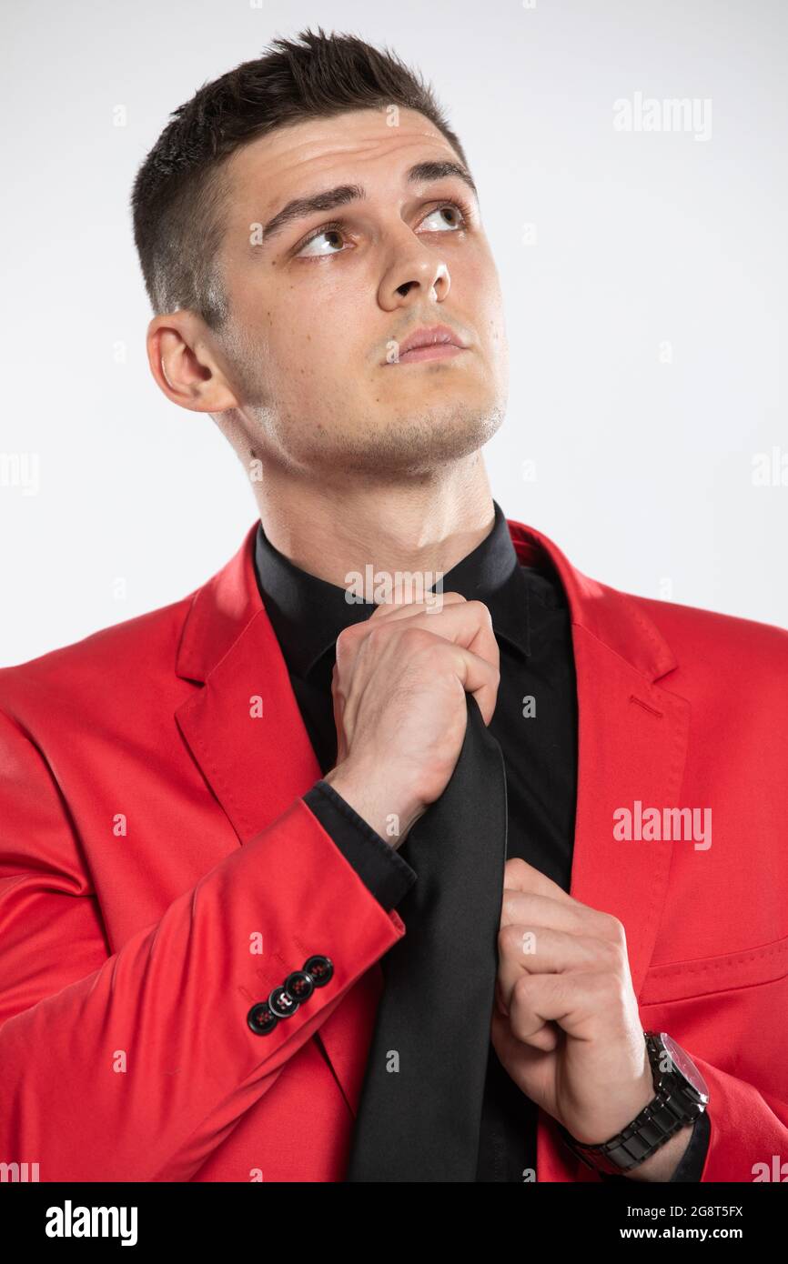 Un jeune homme élégant dans un blazer rouge et une chemise noire, retweed  sa cravate Photo Stock - Alamy