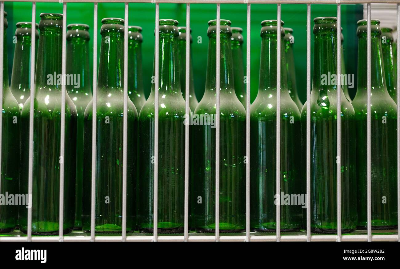 Beaucoup de bouteilles de bière en verre vert transparent et poussiéreux dans la rangée, gros plan. Texture de la bouteille en verre.. Banque D'Images
