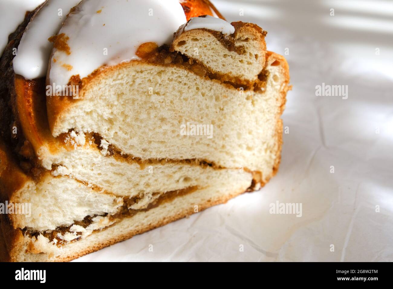 Rouleau de cannelle ou petit pain à la cannelle dessert sur papier blanc. Soleil et ombres. Gros plan Banque D'Images