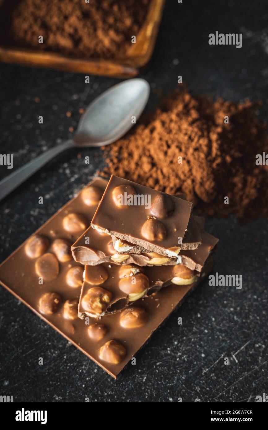 Chocolat à la noisette avec noisettes et poudre de cacao sur table noire. Banque D'Images