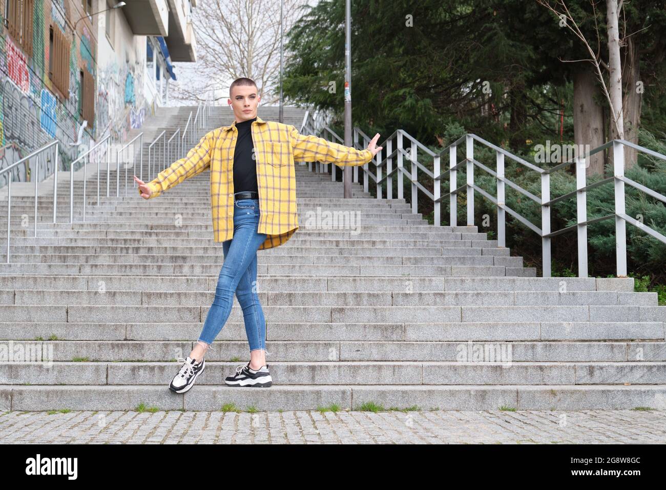 Jeune personne non binaire dansant et écoutant de la musique dans la rue. Faites le maquillage de la personne androgyne. Banque D'Images