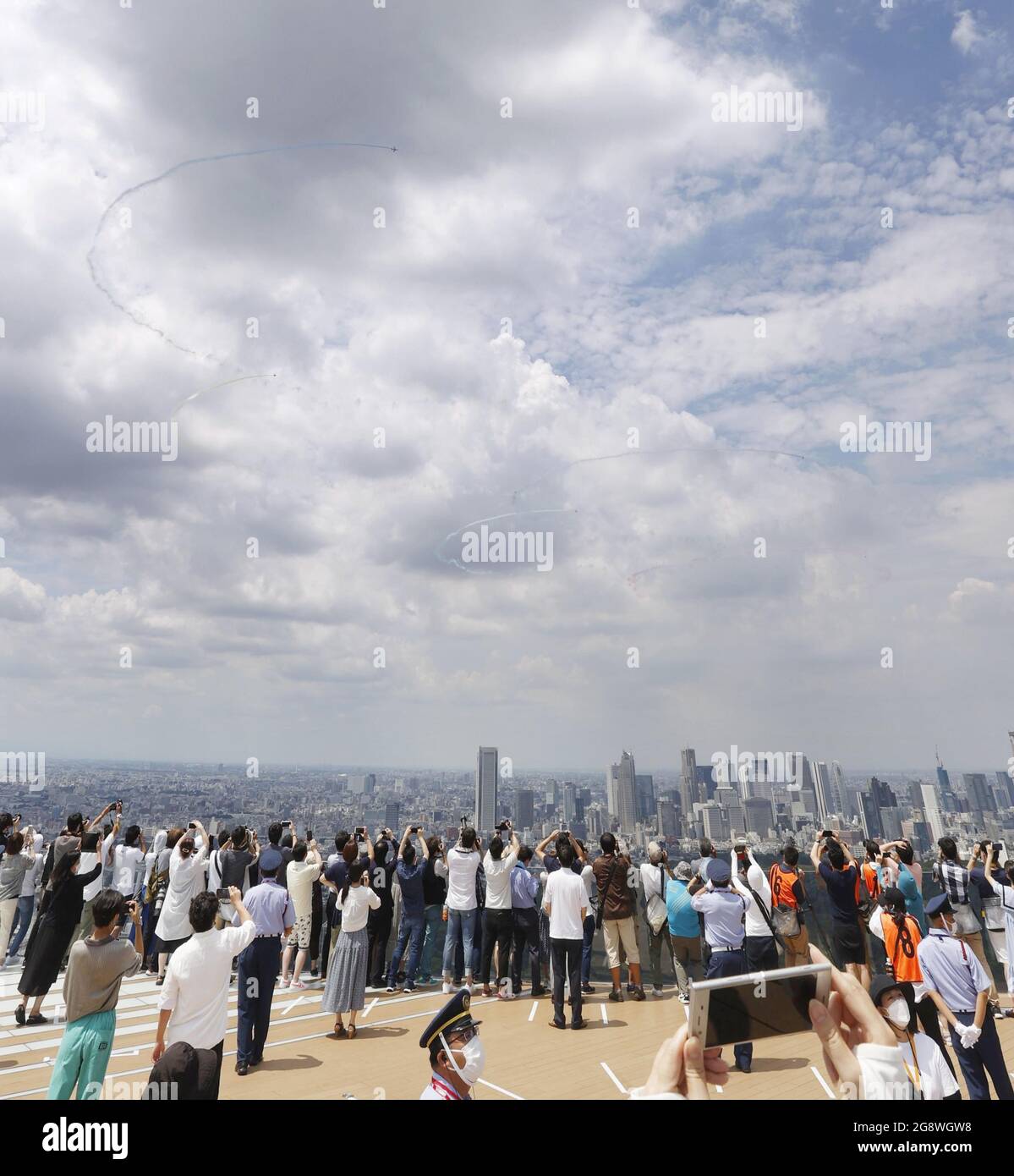 Tokyo, Japon, 23 juillet 2021. Les gens regardent l'équipe aérobie Blue Impulse de la Force aérienne japonaise former les cinq anneaux olympiques avec de la fumée dans le ciel au-dessus du centre de Tokyo le 23 juillet 2021, avant la cérémonie d'ouverture des Jeux Olympiques de Tokyo plus tard dans la journée. (Kyodo)==Kyodo photo via crédit: Newscom/Alay Live News Banque D'Images