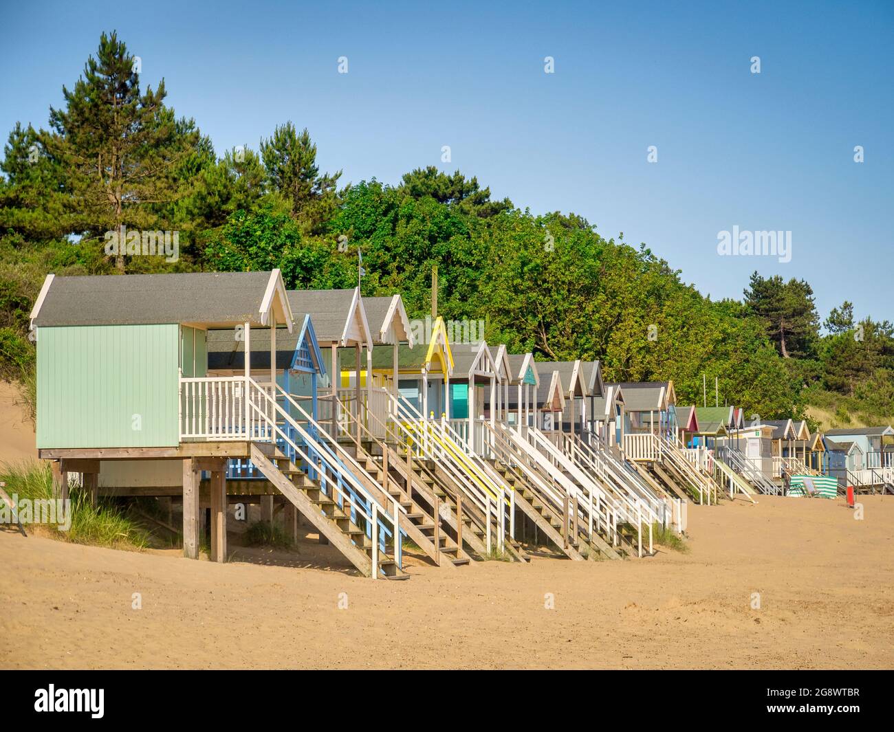 29 juin 2019: Wells-Next-the-Sea, Norfolk, Angleterre, Royaume-Uni - cabines de baignade sur la plage, arbres derrière. Banque D'Images