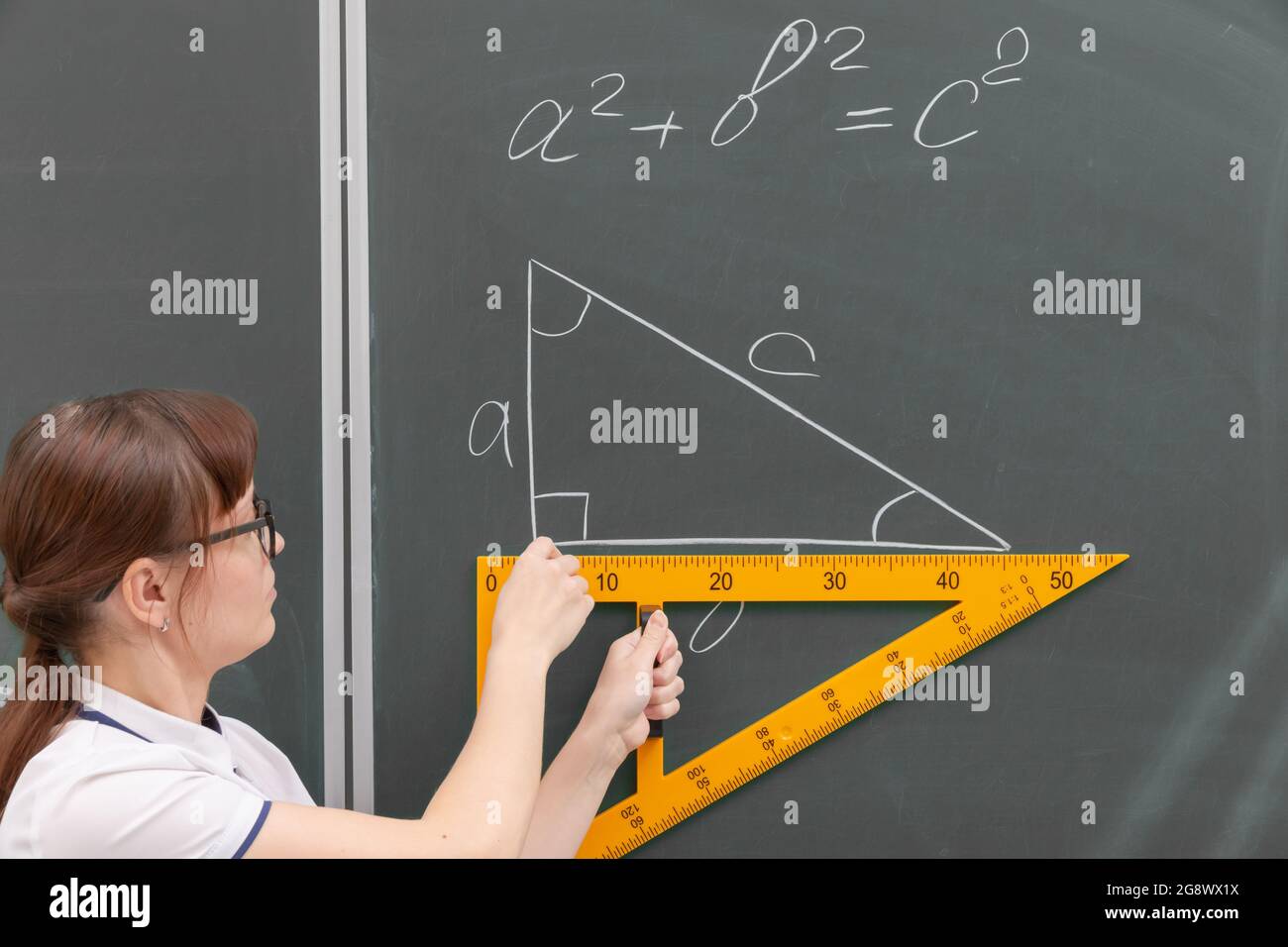 professeur d'école la jeune femme en classe au tableau noir dessine un triangle avec une règle. portrait. gros plan Banque D'Images