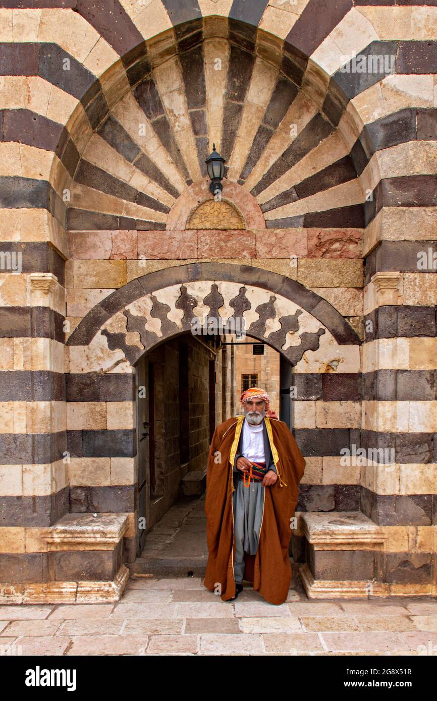 Homme local en vêtements traditionnels devant la porte de la mosquée historique de Sanliurfa, Turquie Banque D'Images